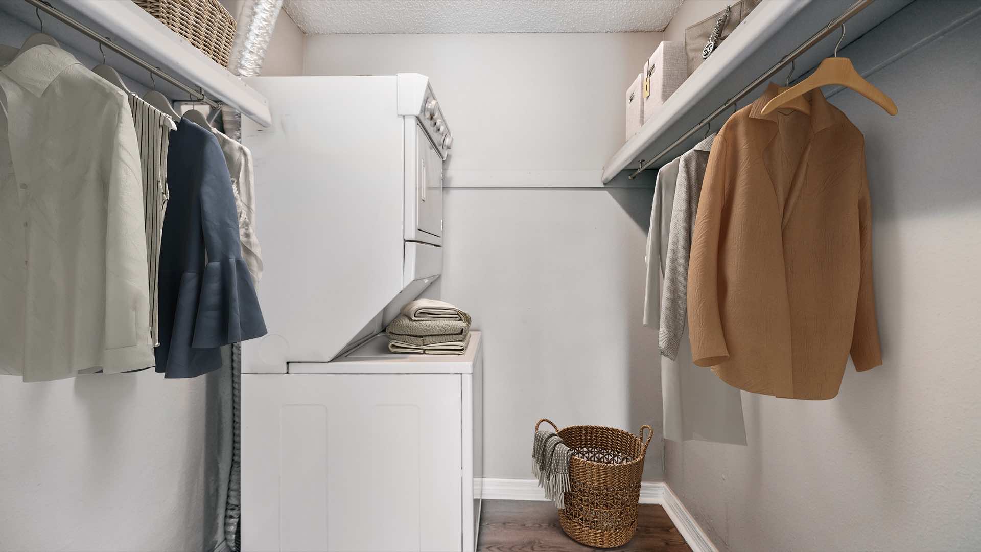 spacious walk-in closet with clothes hanging and stacked washer and dryer unit